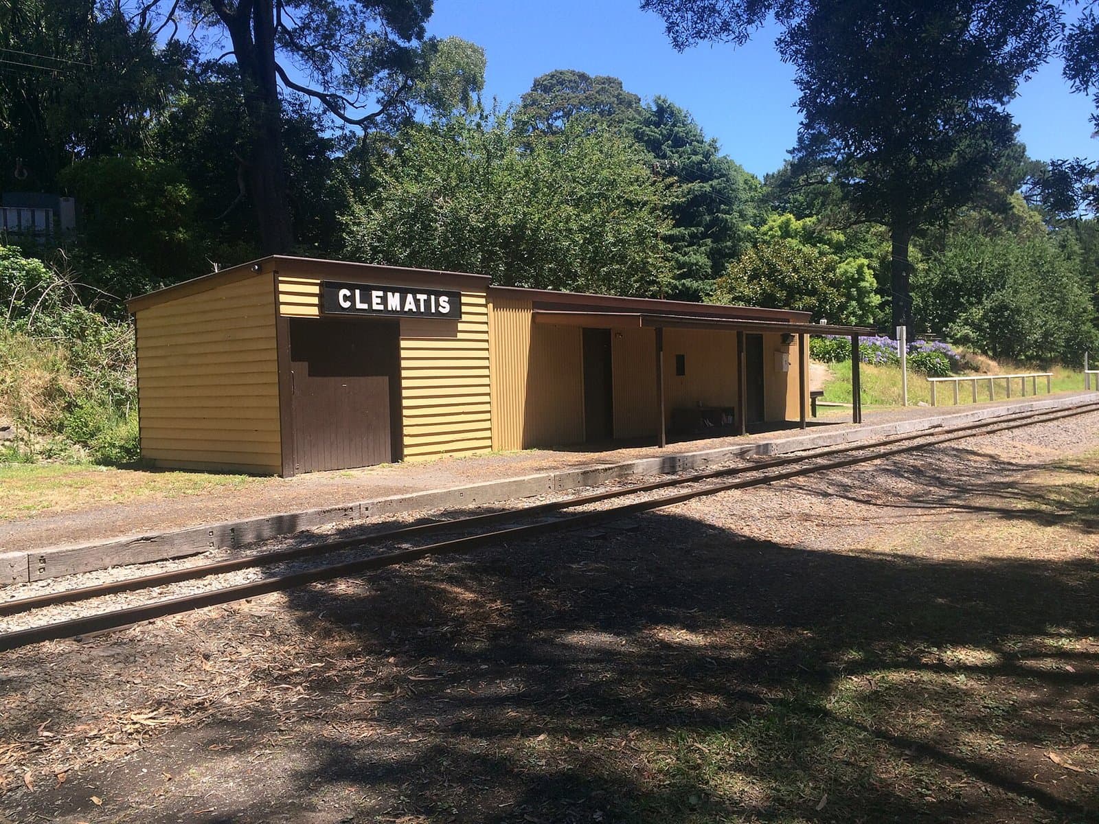 A small cream station building beside the railway line, with trees behind