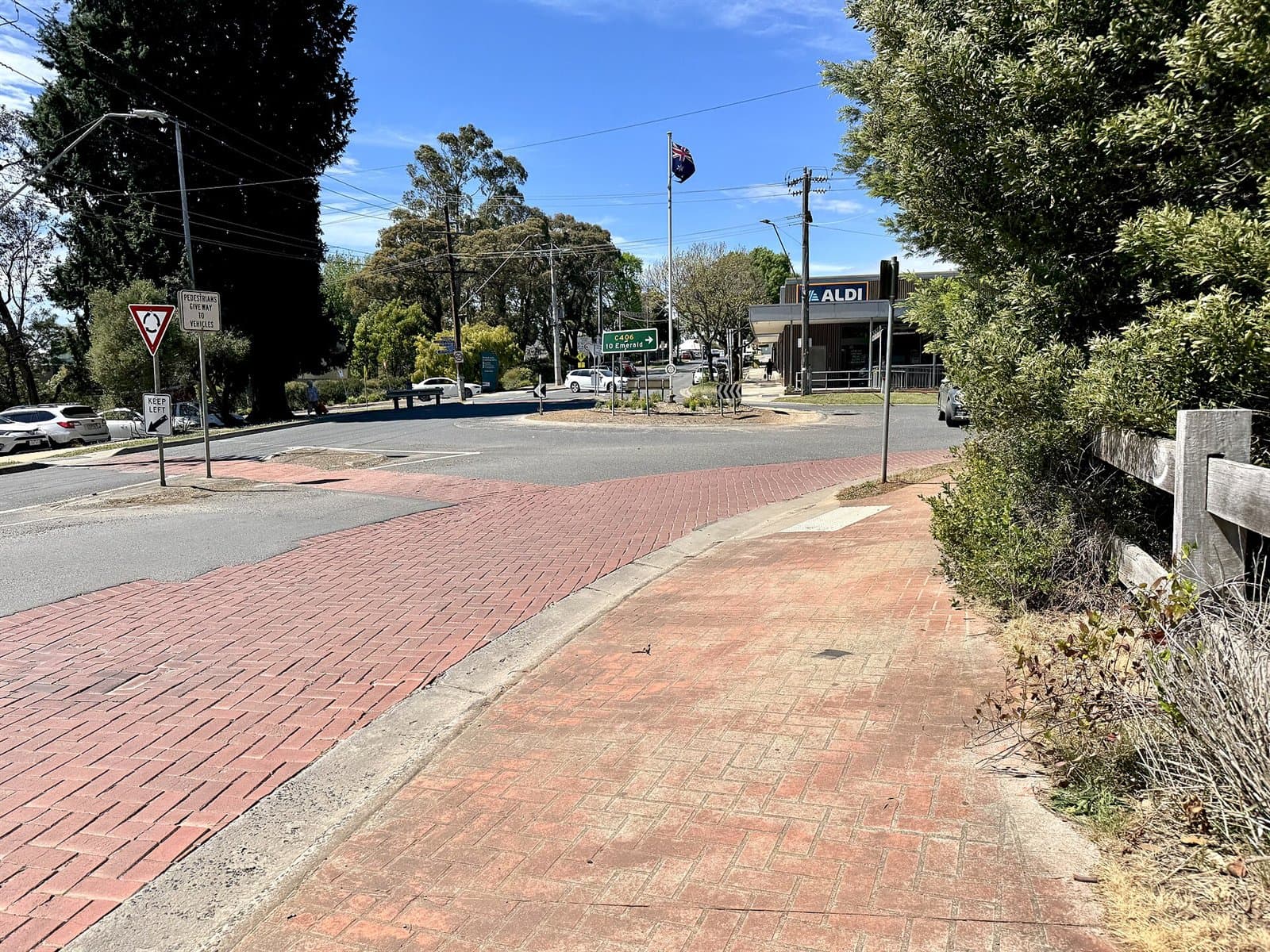 A footpath beside Main Road leading to a roundabout at the edge of the Monbulk shops